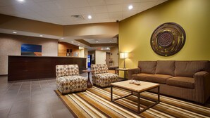 Un vestíbulo con mostrador de recepción, sillones estampados, un sofá y una mesa de centro.