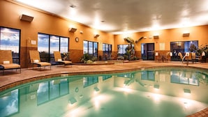 Una piscina con sillones de descanso y vistas al cielo a través de amplias ventanas.