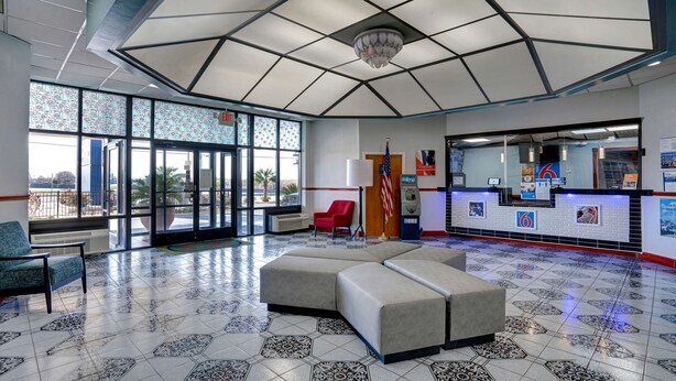 A spacious lobby with a large seating area, a reception desk, and large windows offering views of the outside. - Motel 6 Burlington, NC (Burlington)