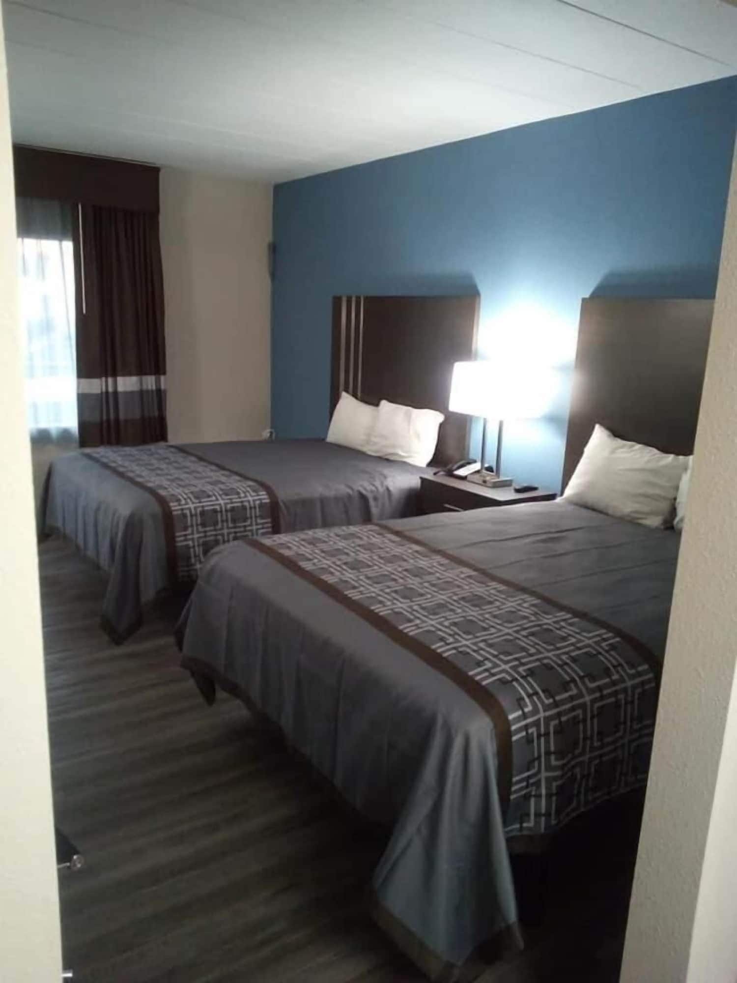 Une chambre d’hôtel avec deux lits, une table de chevet et une lampe.