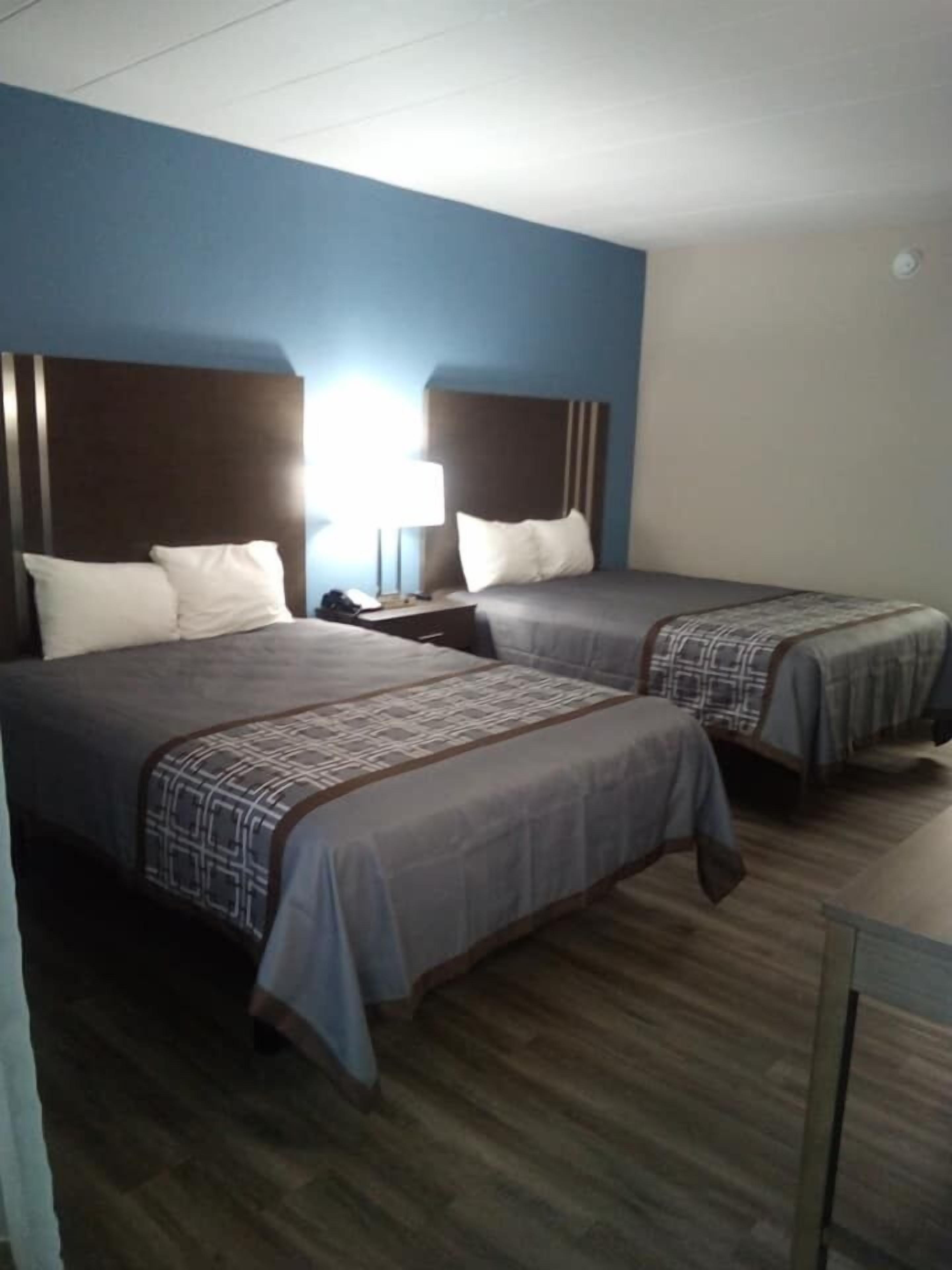 Una habitación de hotel con dos camas, una mesita de noche y una lámpara.