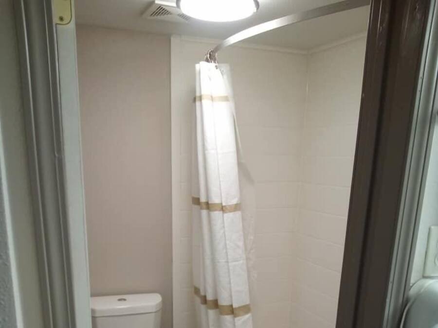 A small bathroom with a toilet, a shower with a curtain, and a bathtub.
