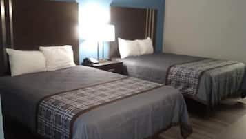 A hotel room with two beds, a nightstand, and a desk.
