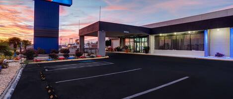 A hotel with a prominent '6' sign, a parking lot, and a modern building facade.