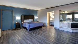 A modern hotel room with a large bed, bedside lamps, a built-in desk, and a bathroom with a large mirror and sink. - Motel 6 Burlington, NC (Burlington)