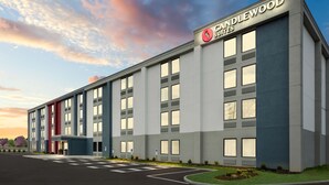 Een modern hotelgebouw met een goed zichtbaar “Candlewood Suites” bord, meerdere ramen en een parkeerplaats.