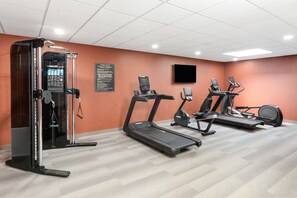 Un gimnasio con cintas de correr, elípticas y máquinas de pesas.