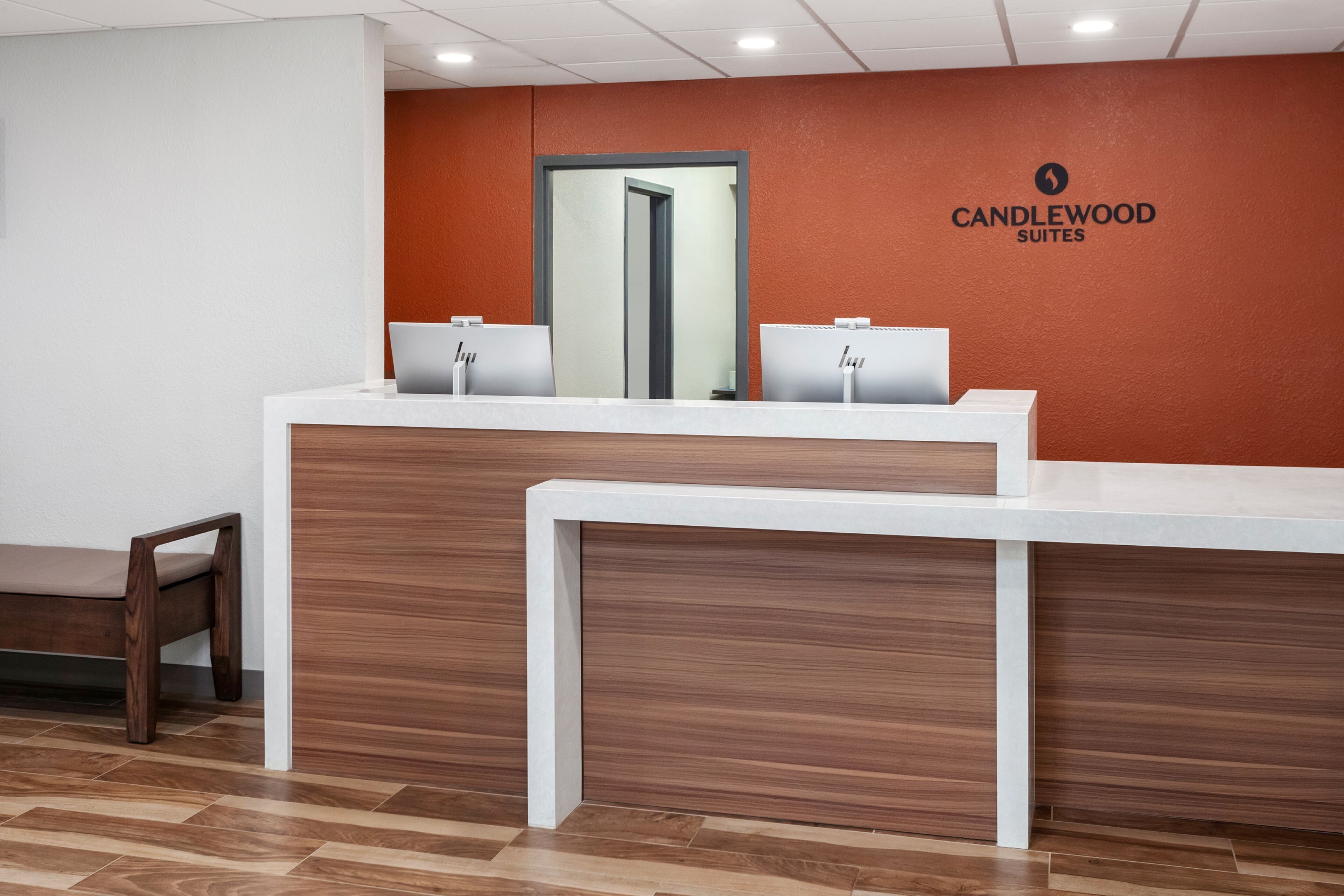 A reception desk with a mirror, two computer stations, and a bench.