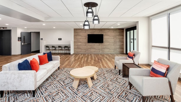 Een moderne lobby met een witte bank, fauteuils, een houten salontafel en een kamerbreed tapijt met een patroon.