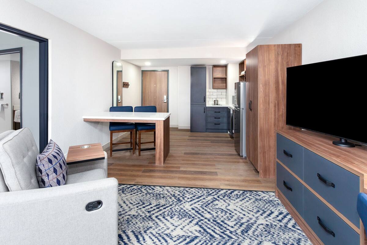 Een compacte hotelkamer met een kitchenette, een eethoek en een televisie.