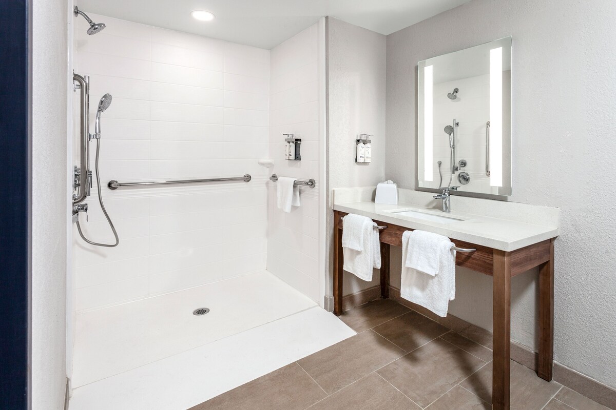 Une salle de bain moderne avec une douche à l’italienne, un meuble-lavabo avec un miroir et un porte-serviettes.