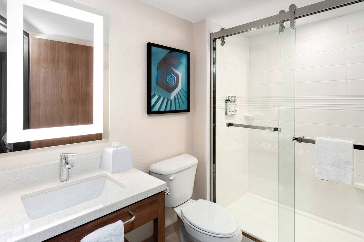 Een moderne badkamer met een douchecabine van glas, een wit wastafelmeubel en een toilet.