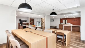 Een modern café met houten tafels en stoelen, een koffieapparaat en een toonbank met een menu.