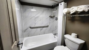 A bathroom with a bathtub, toilet, and a shower area with a glass door. - Baymont by Wyndham Lafayette (Lafayette)