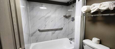 A bathroom with a bathtub, toilet, and a shower area with a glass door.