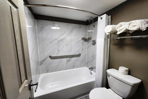 A bathroom with a bathtub, toilet, and a shower area with a glass door.