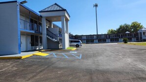 A motel with a covered outdoor area, a parking lot, and a building with multiple floors and balconies. - Baymont by Wyndham Lafayette (Lafayette)