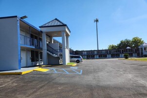 A motel with a covered outdoor area, a parking lot, and a building with multiple floors and balconies.