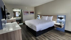 A modern hotel room with a large bed, bedside tables, a desk, and a mirror. - Baymont by Wyndham Lafayette (Lafayette)