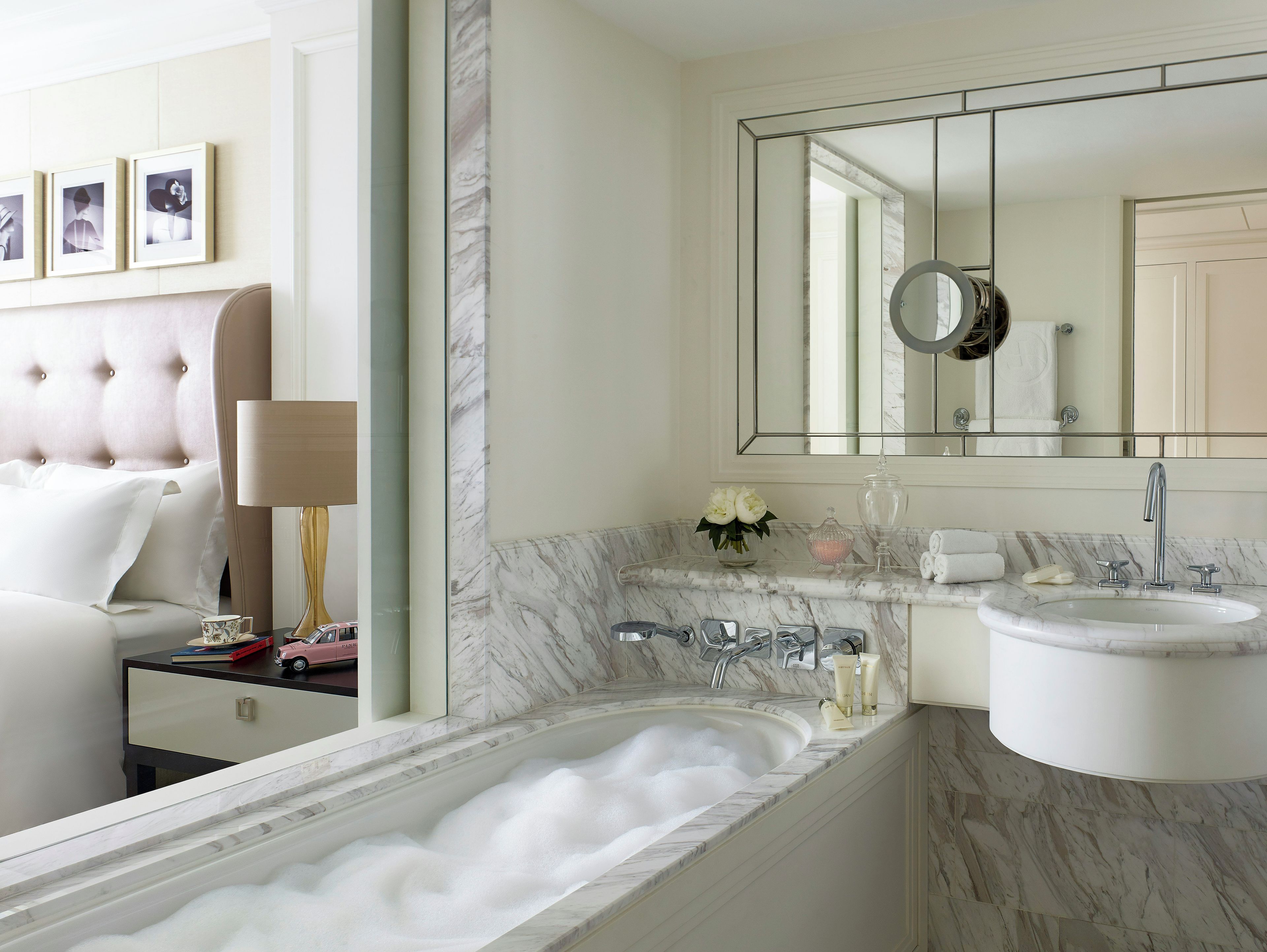Un baño moderno con un lavabo de mármol, un espejo grande y una bañera llena de burbujas.