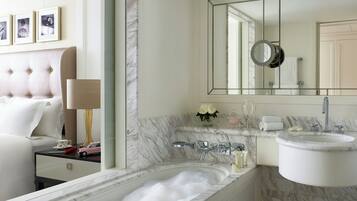 Un baño moderno con un lavabo de mármol, un espejo grande y una bañera llena de burbujas.