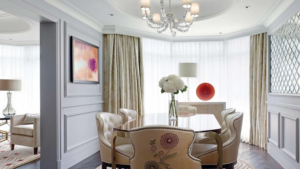 A formal dining room with a chandelier, elegant chairs, a table, and a vase of flowers.