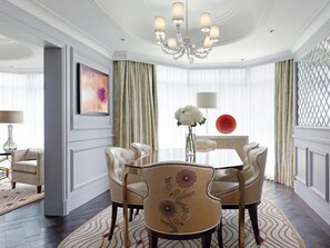 Un comedor formal con candelabro, sillas elegantes, una mesa y un jarrón de flores.
