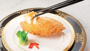A plate with a breaded item, a green vegetable, and a red chili.