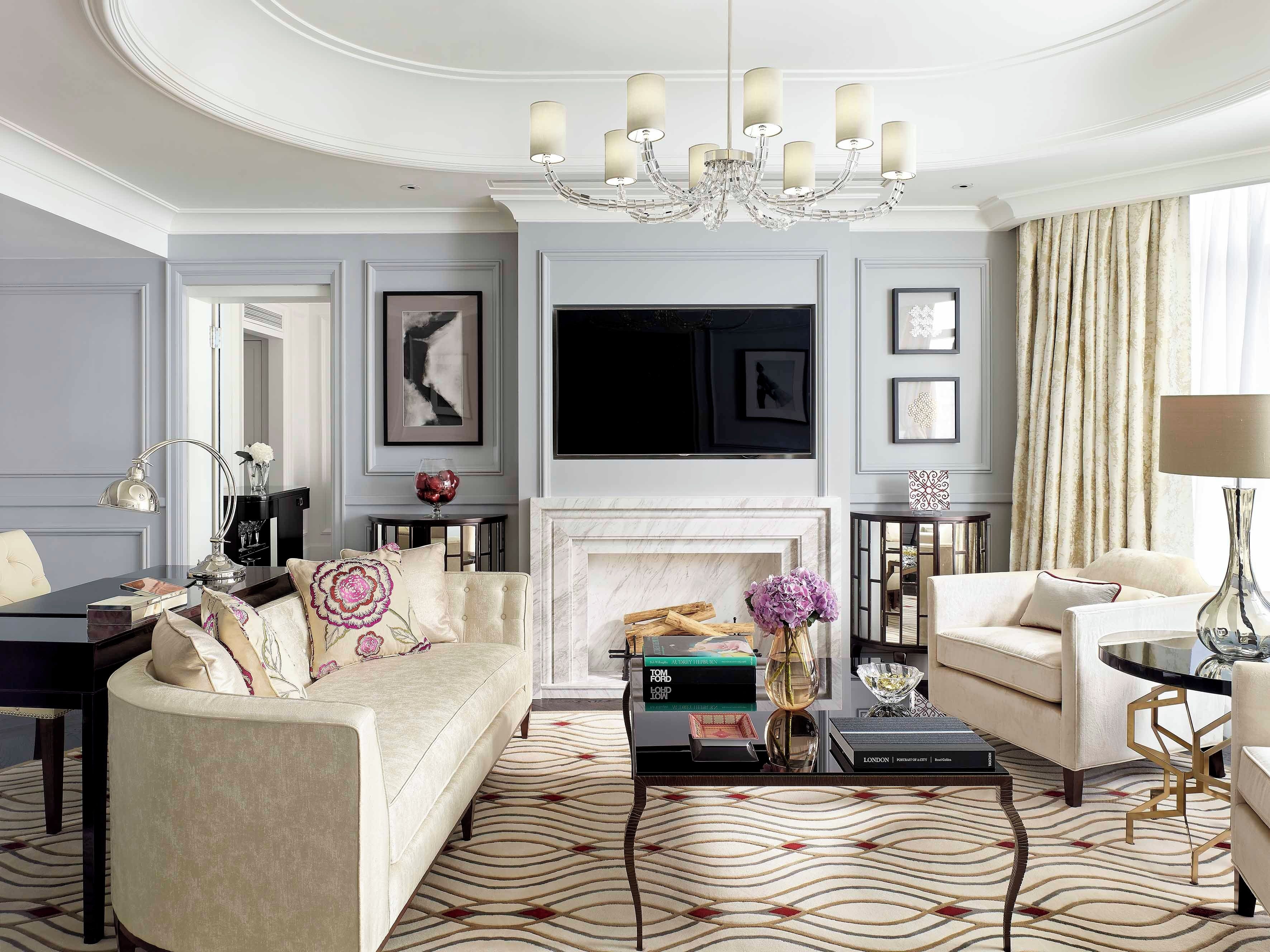 A living room with a fireplace, a chandelier, and a television mounted on the wall.