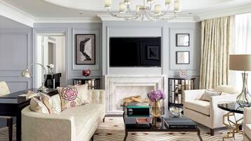A living room with a fireplace, a chandelier, and a television mounted on the wall.