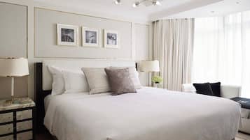 A hotel room with a large bed, bedside lamps, a nightstand, a dresser, and a chandelier.