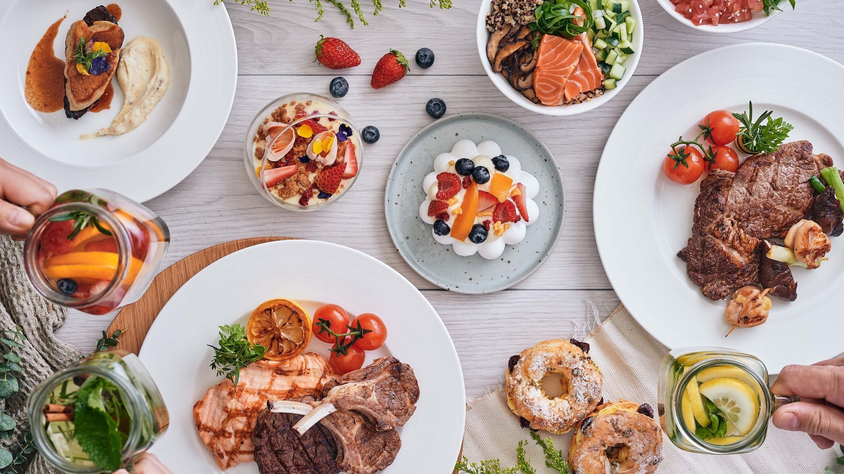 A variety of dishes including grilled meat, salmon, and fruit salads, suggesting a meal setting.