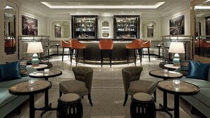 A bar area with a central bar, two sofas, and a chandelier.