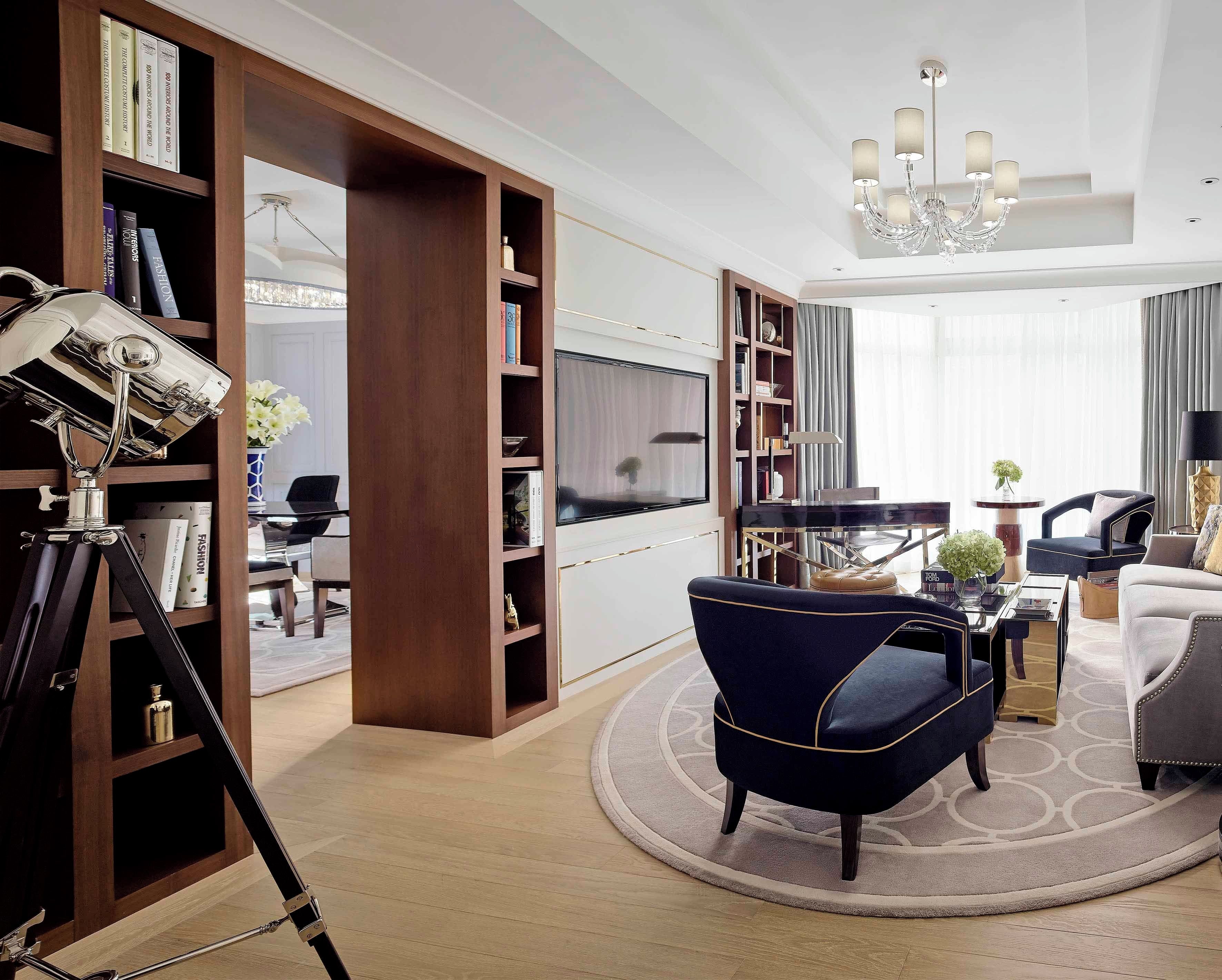 A modern living room with a large bookshelf, a television, a piano, and a chandelier.