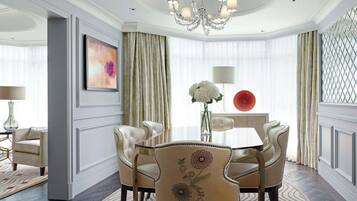 A formal dining room with a chandelier, a table, chairs, and a vase with flowers.