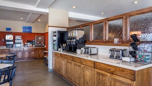 A spacious kitchen with wooden cabinets, a large island, and various appliances including a coffee machine, toaster, and refrigerator. - Best Western Desert Inn (West Yellowstone)