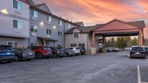 A hotel with a covered parking area and multiple cars parked. - Best Western Desert Inn (West Yellowstone)