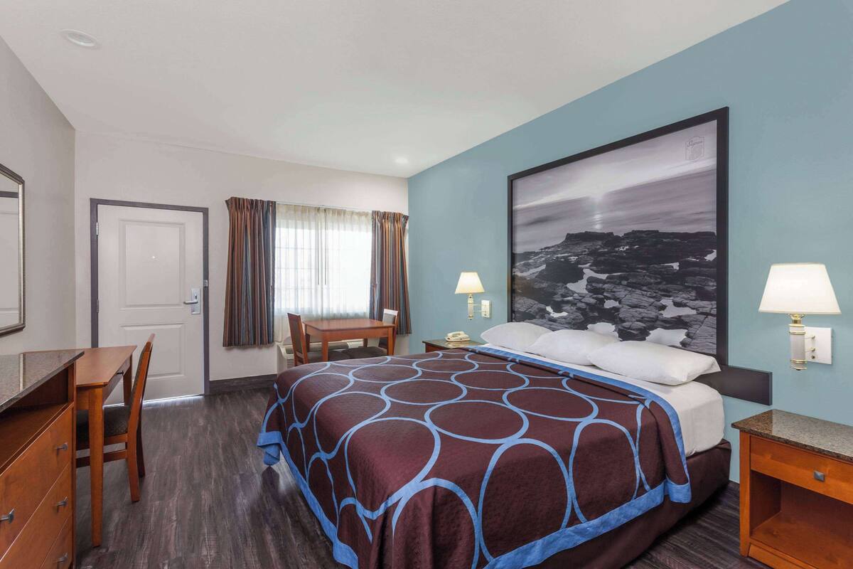 A hotel room with a large bed, a desk, and a chair.