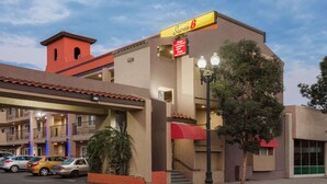 Un hotel con toldo rojo, un letrero que dice "Super 8" y un estacionamiento con varios coches.