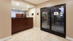 Una zona de recepción con un mostrador de madera, un reloj y una puerta de cristal que da a una escalera.