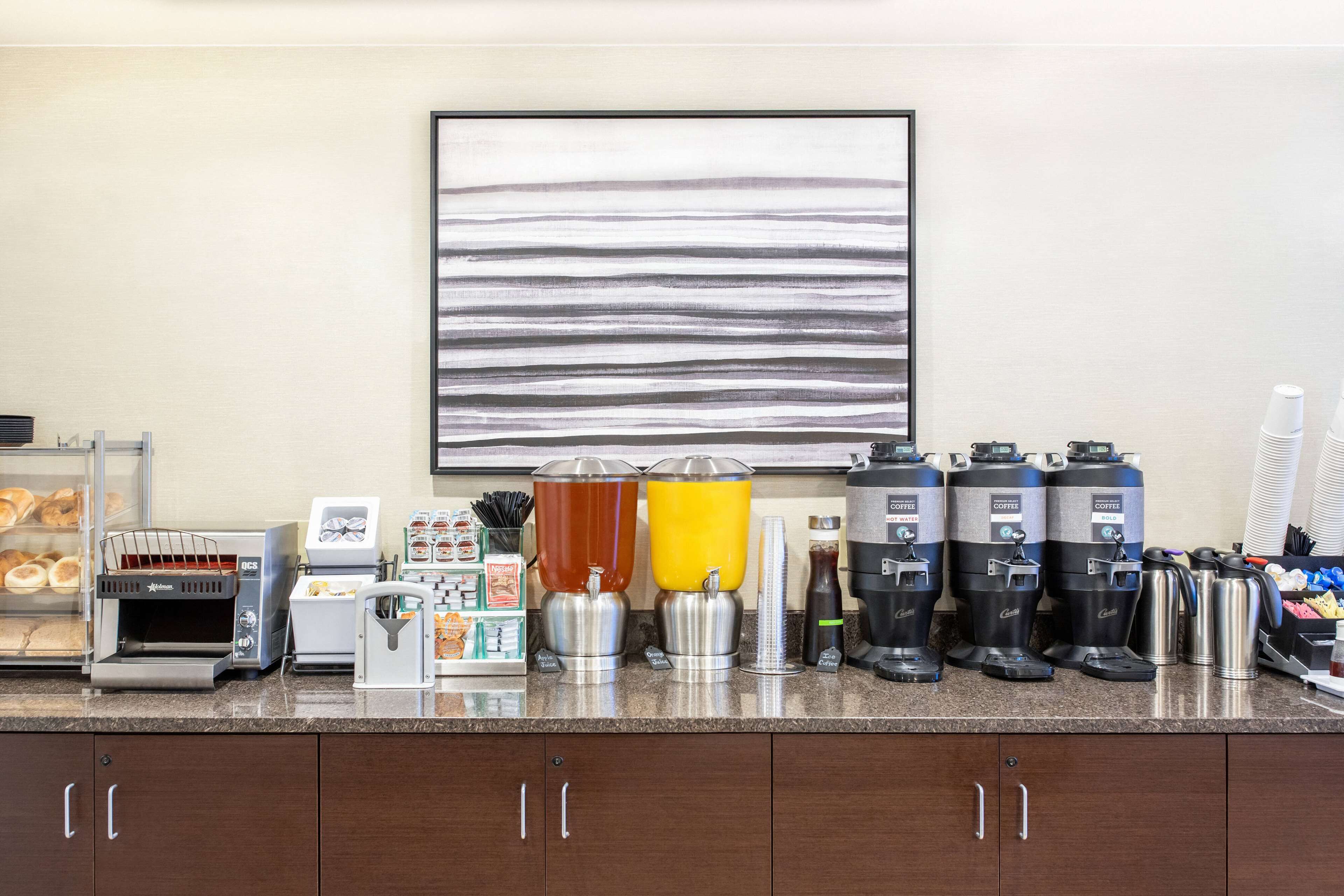 Una estación de café con varias cafeteras, un tostador y una exhibición de pan.