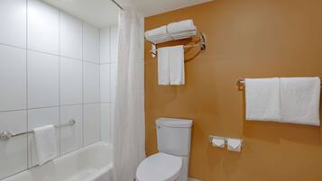 A bathroom with a bathtub, toilet, and towel rack.