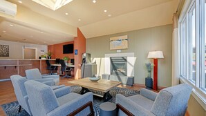 Una sala de estar moderna con chimenea, zona de estar y una cocina al fondo.