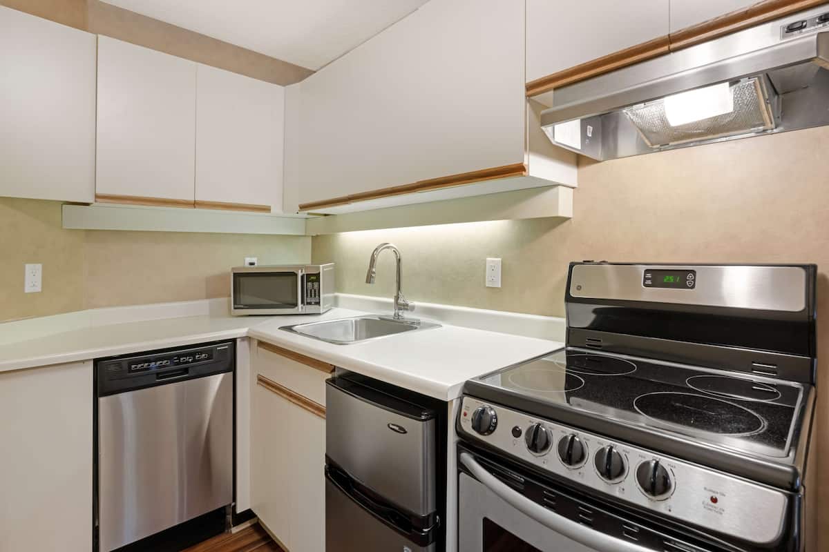 A compact kitchen with a dishwasher, microwave, sink, and stainless steel stove.