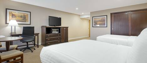 Een hotelkamer met een bed, een bureau met stoel, een televisie en een kledingkast.