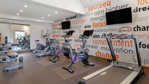 Un gimnasio moderno con bicicletas estáticas, cintas de correr y máquinas de pesas.
