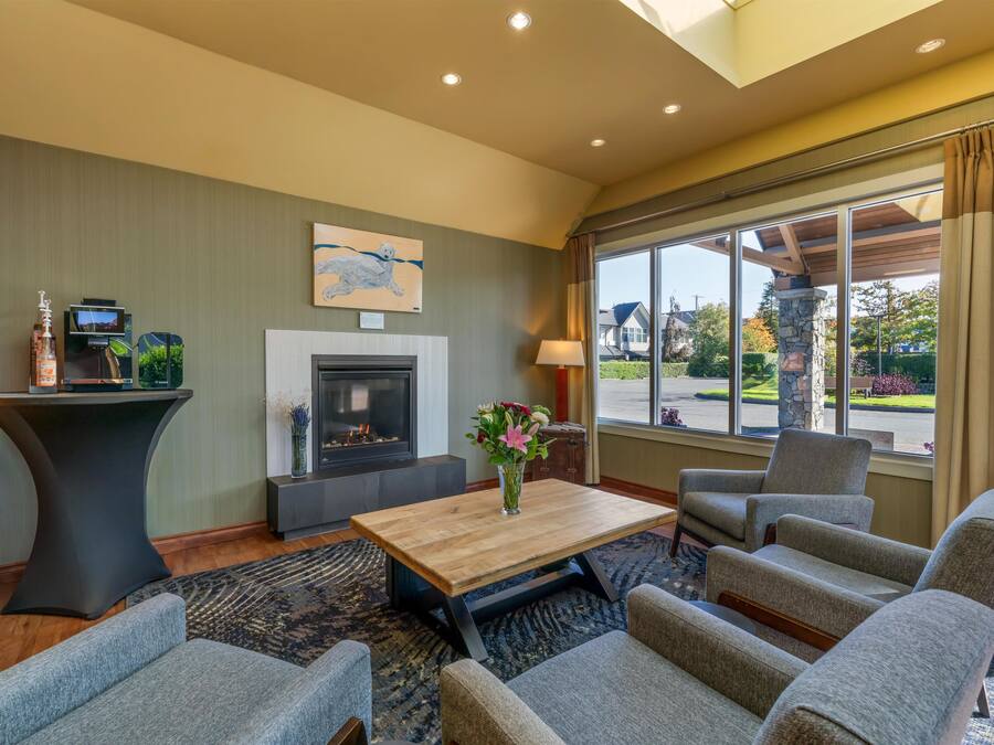 A modern living room with a fireplace, comfortable seating, and a large window offering a view of the outdoors.