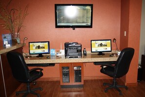 Un mostrador de recepción con dos monitores de computadora, una impresora y dos sillas de oficina.