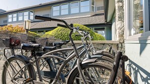 Una bicicleta estacionada frente a un edificio con fachada de piedra y ventanas grandes.