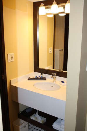 Un baño con un lavabo blanco, un espejo y un toallero.